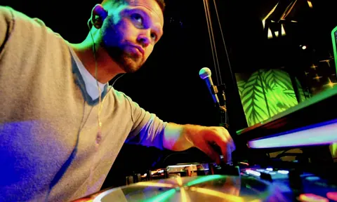 DJ Wayne Noel mixing under colored club lights at 1015 Folsom, San Francisco