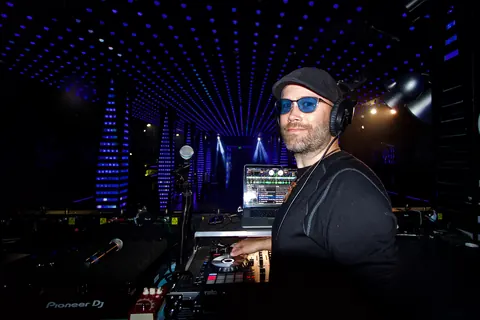 DJ Wayne Noel in tinted glasses and headphones mixing at Temple nightclub in San Francisco under a ceiling of blue LED lights