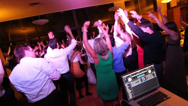 Guests with hands raised on the dance floor at Alumni House, UC Berkeley, photographed from DJ Wayne Noel's booth