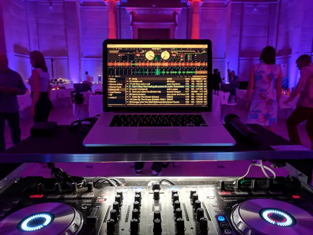 View from behind Wayne Noel's DJ controller and laptop with guests dancing in the purple uplit hall at the Asian Art Museum in San Francisco