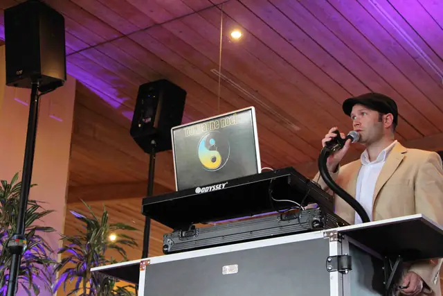 DJ Wayne Noel on the microphone behind his DJ booth at Auberge du Soleil in Rutherford, under a wood ceiling washed in purple light