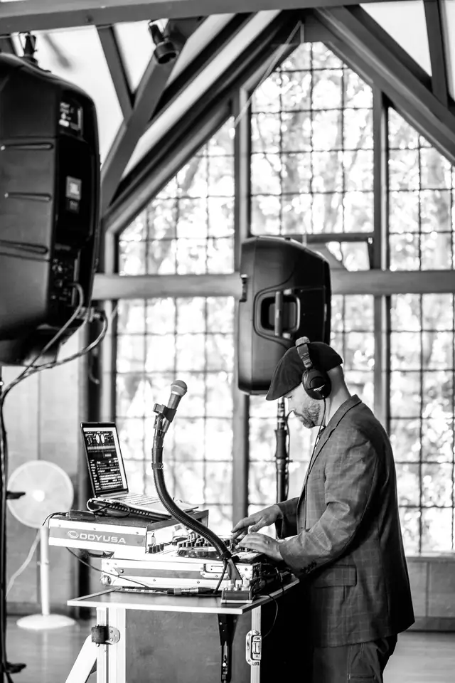 DJ Wayne Noel mixing at his setup under the wooden roof trusses and tall windows of the Brazilian Room in Tilden Park, Berkeley