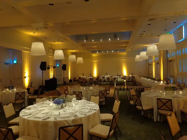 Event room at Carneros Resort and Spa with a DJ booth, two speakers on stands and amber uplighting around set dinner tables