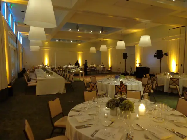 Event room at Carneros Resort and Spa set with a long table and round tables, with DJ speakers and booth at the right under amber uplighting
