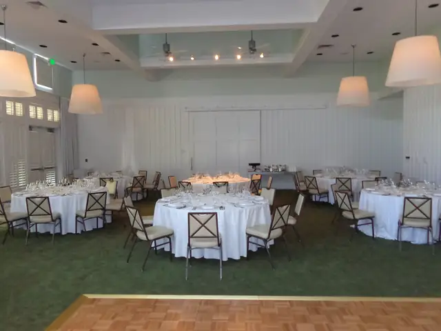 White-walled event room at Carneros Resort and Spa in daylight with white pendant lamps, round tables and a parquet dance floor