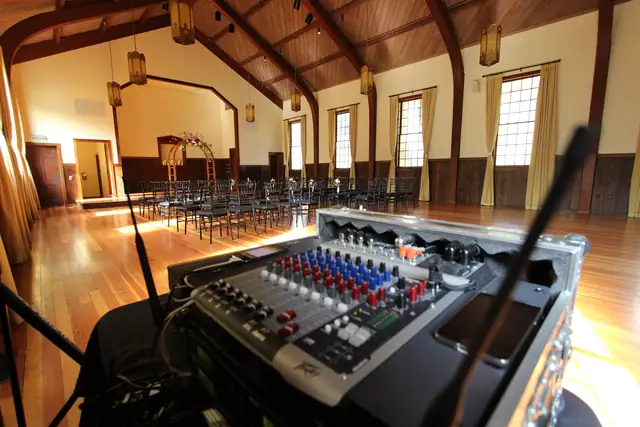 DJ Wayne Noel's ceremony mixer set up in front of rows of chairs and the floral arch in the timber hall at Cavallo Point