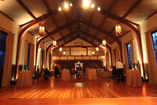 Warm evening light in the arched timber hall at Cavallo Point with hanging lanterns and cocktail tables on the wood floor