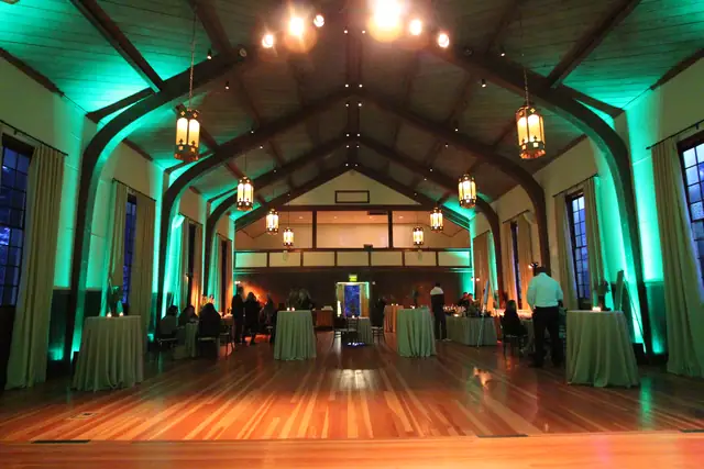 Teal uplighting in the arched timber hall at Cavallo Point with lanterns and cocktail tables