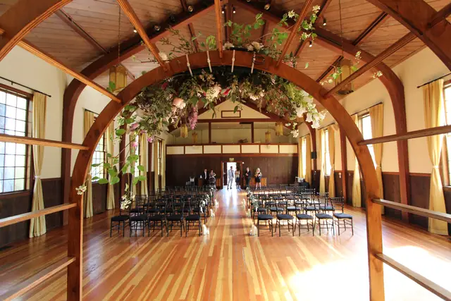 Floral wooden arch framing the ceremony aisle and chairs in the timber-beamed hall at Cavallo Point, Sausalito