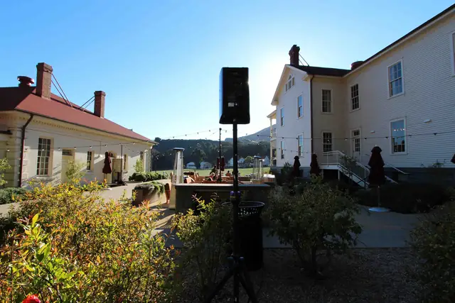 Outdoor courtyard with string lights and a DJ speaker on a stand between the historic white buildings at Cavallo Point