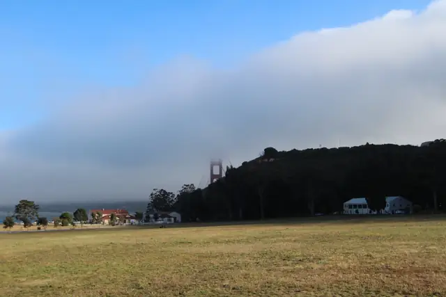 Fog over the hills and a Golden Gate Bridge tower behind the lawn at Cavallo Point in Sausalito
