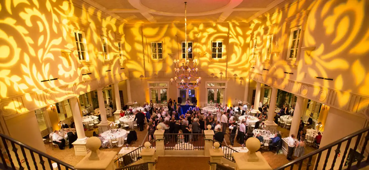Ballroom at The Club at Ruby Hill seen from the staircase, walls covered in amber pattern lighting above a busy dance floor