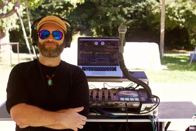 DJ Wayne Noel with headphones at his outdoor DJ booth and laptop at Dawn Ranch in Guerneville