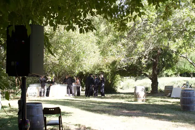 Speaker, wine barrels and cocktail tables under shade trees at the Dawn Ranch apple orchard