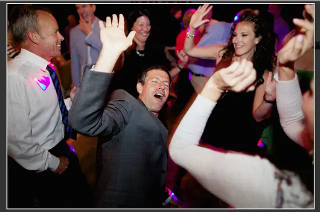 Wedding guests dancing and laughing under colored lights in the Apple Orchard at Dawn Ranch in Guerneville
