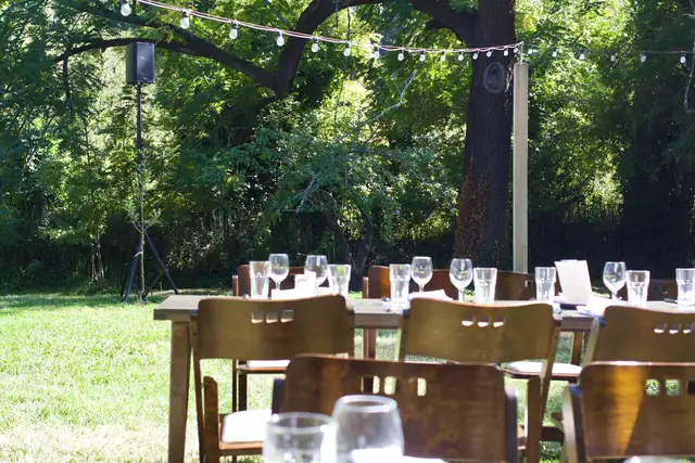 Rustic plank tables and glassware with a DJ speaker among the trees at Dawn Ranch