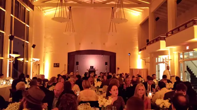 Wayne Noel's DJ setup on the stage of the Golden Gate Club ballroom in San Francisco, with amber uplighting, chandeliers and seated dinner guests