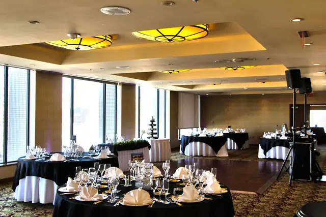 Reception set up in a ballroom at Hotel Nikko San Francisco with black linen tables, a wood dance floor, window walls and DJ speakers on stands