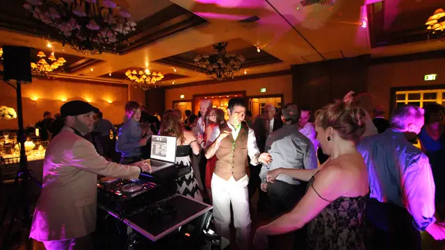 DJ Wayne Noel mixing at his booth beside a crowded dance floor in the ballroom at The Inn at Spanish Bay in Pebble Beach