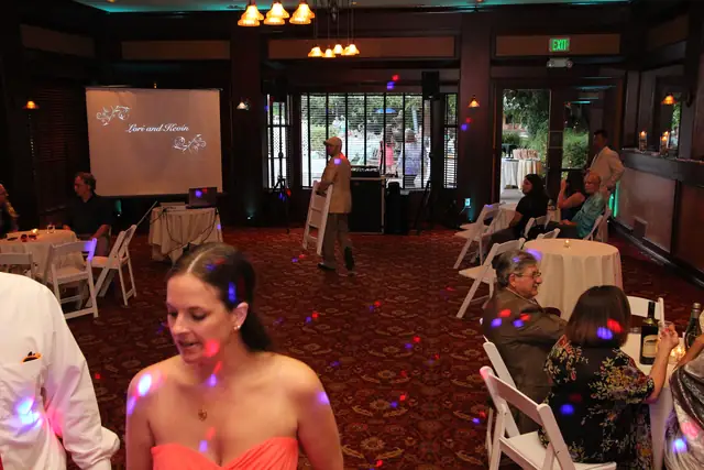 DJ Wayne Noel's booth and speakers set up by the garden windows in the banquet room at Inn Marin, with teal uplighting