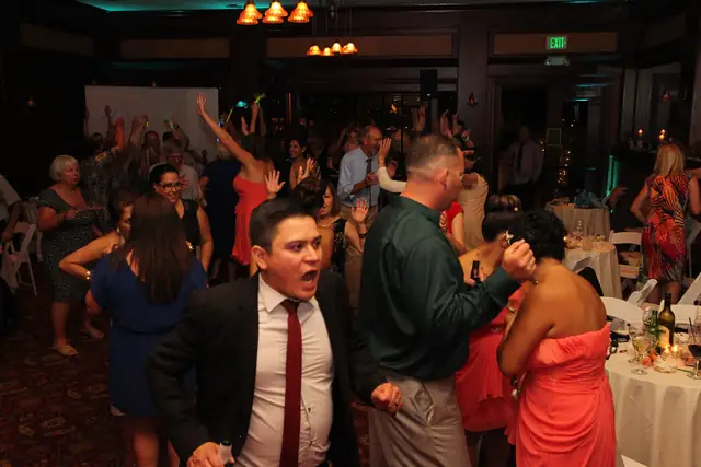 Wedding guests dancing with arms raised on a full dance floor in the banquet room at Inn Marin in Novato