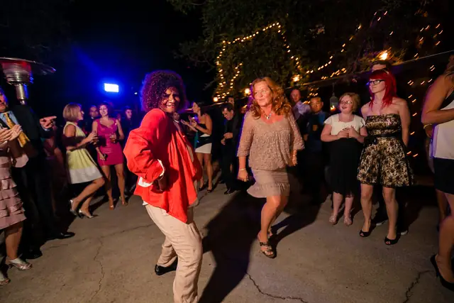 Guests dance in a circle under a tree wrapped in string lights on the patio at Little Hills in San Ramon