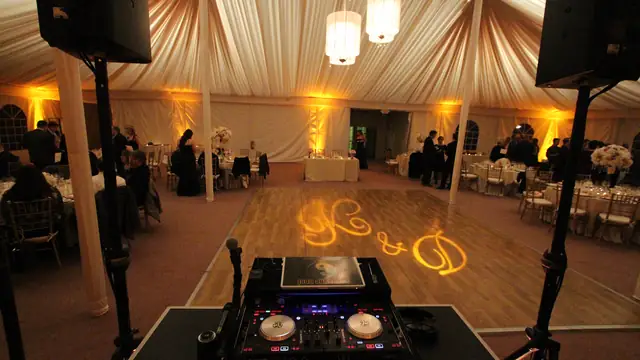 DJ controller and speakers facing the dance floor inside the draped tent at The Lodge at Sonoma