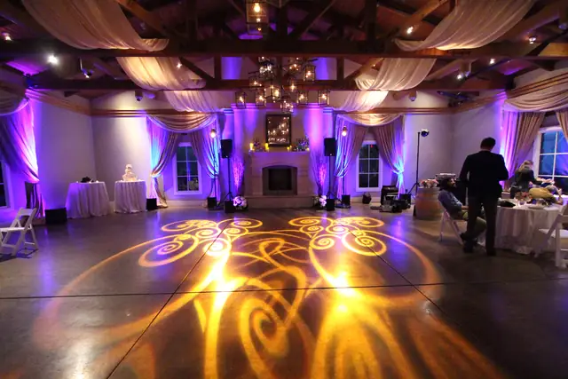 The Lodge at Sonoma Stone Room with amber pattern lighting on the floor, fireplace, speakers and purple uplit drapes