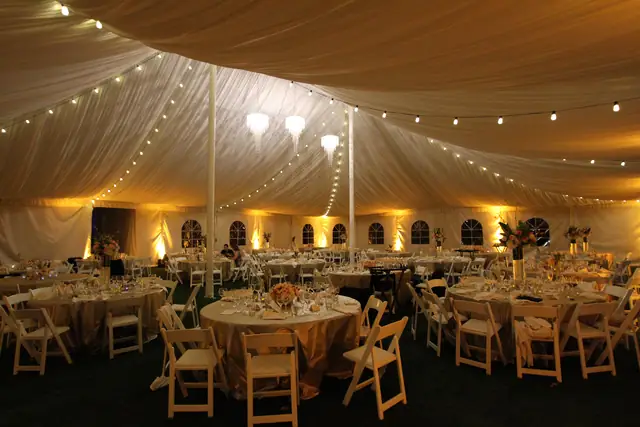 Wide view inside the dinner tent at The Lodge at Sonoma with string lights and warm uplighting