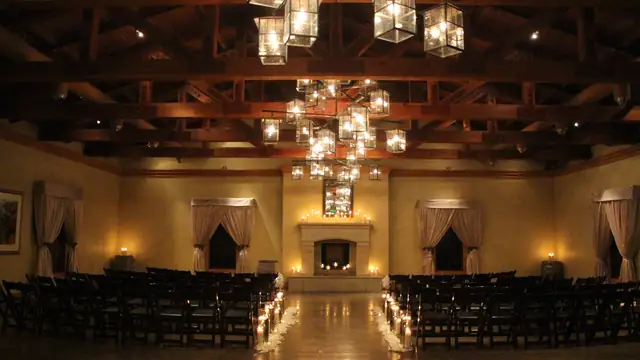 Ceremony seating and candlelit aisle in the Stone Room at The Lodge at Sonoma, facing the fireplace