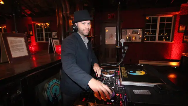 DJ Wayne Noel at the decks beside the bar at Long Branch Saloon, Half Moon Bay, with red uplighting behind him