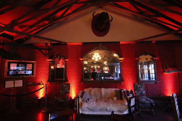 Red uplighting on the damask wall, antique mirrors and buffalo head at Long Branch Saloon, Half Moon Bay