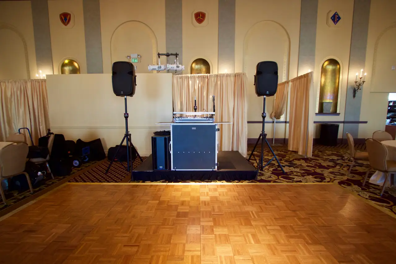 Wayne Noel's DJ setup with two speakers and a subwoofer on a riser in the Marines' Memorial Club ballroom in San Francisco, facing the parquet dance floor