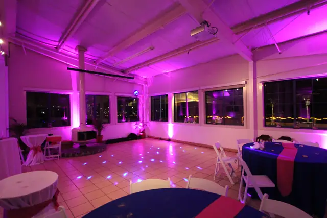Tile dance floor at Mavericks House lit with pink uplighting and blue points of light beside the round white fireplace