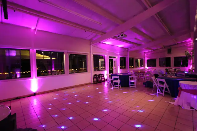 Pink uplighting along the window wall of the reception room at Mavericks House at night