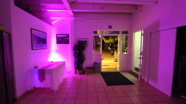 Entry area at Mavericks House with an open door and pink uplighting on the white walls