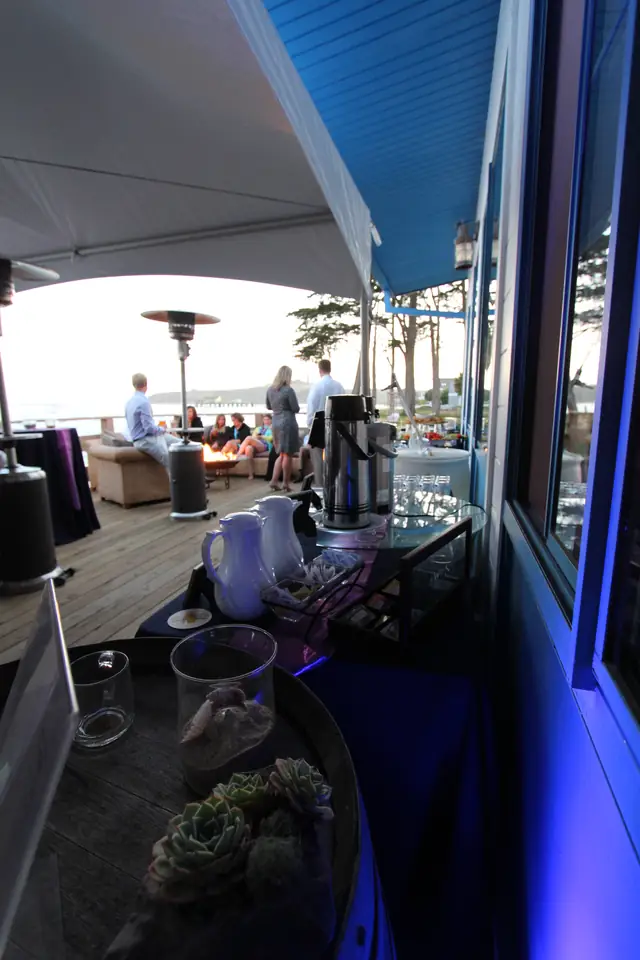 Deck at Mavericks House at sunset with a patio heater, lounge seating, guests and a coffee station beside the window