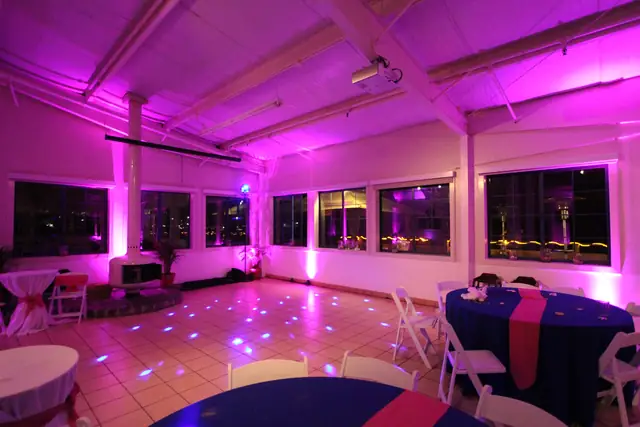 Mavericks House room set with round tables and an open tile dance floor under pink uplighting