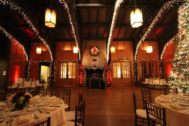 Meadow Club hall at night with the DJ booth in the fireplace, lit arches, lanterns and place settings in the foreground