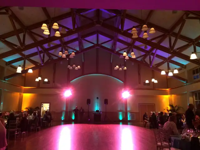 Mill Valley Community Center hall with timber trusses, colored uplighting and a DJ setup at the far end of the dance floor