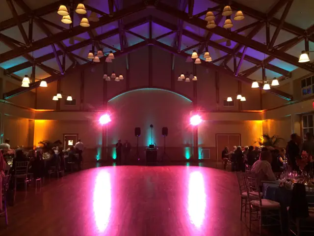 Wood dance floor and timber-truss ceiling at Mill Valley Community Center with a DJ setup at the back wall