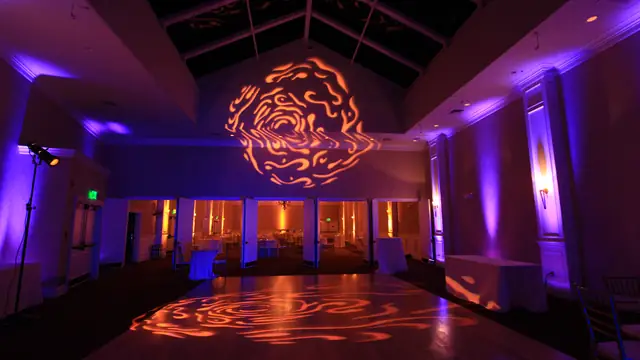 Skylit ballroom at Oceano Hotel and Spa lit with purple uplighting and an orange swirl pattern across the wall and dance floor