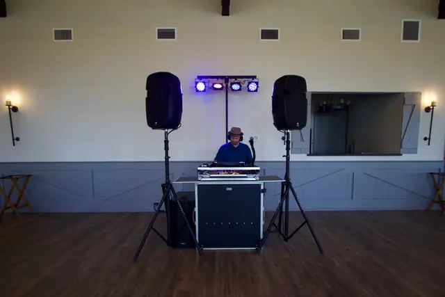 DJ Wayne Noel set up between two speakers with a light bar in the event room at Oceano Hotel and Spa