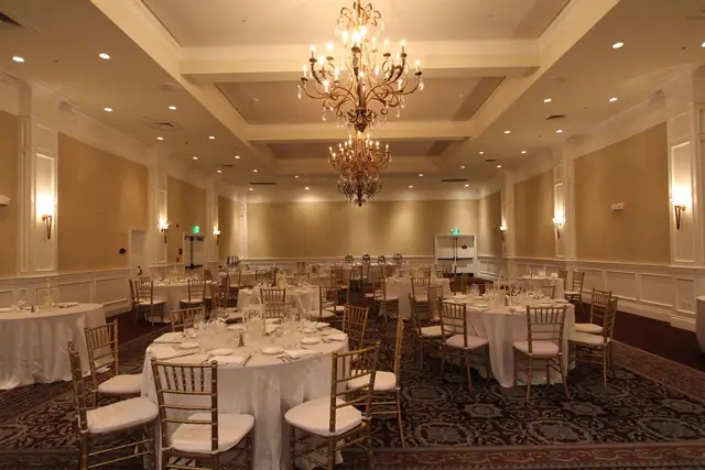 The ballroom at Oceano Hotel and Spa set with round tables and gold chairs under a two-tier chandelier