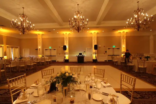 Oceano Hotel and Spa ballroom with warm amber lighting, a white dance floor and the DJ setup at the back wall
