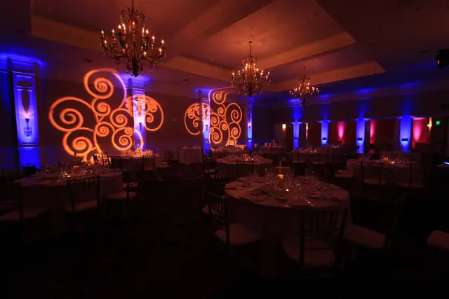 Oceano Hotel and Spa ballroom with blue uplighting and amber swirl patterns on the wall above set dinner tables