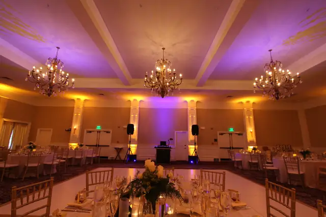 Oceano Hotel and Spa ballroom with purple and amber lighting, three chandeliers and a DJ setup on the far wall behind the dance floor