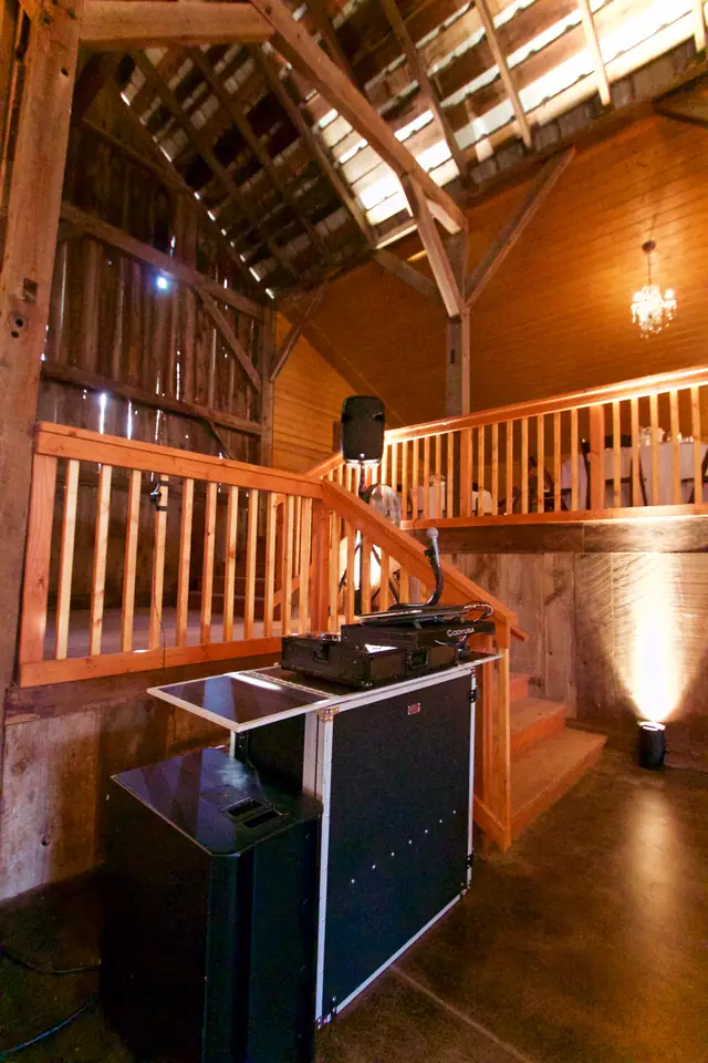 Wayne's DJ booth and speaker set up beside the wooden stairs and balcony inside the barn at Olympia's Valley Estate