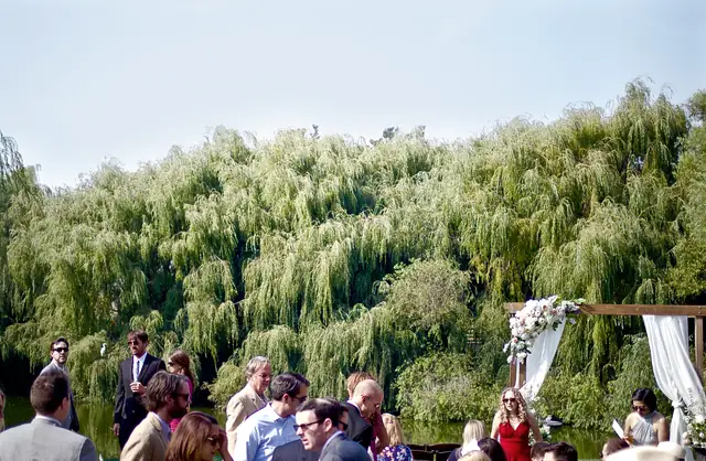 Outdoor ceremony arch with white drapes and flowers in front of weeping willows at Olympia's Valley Estate