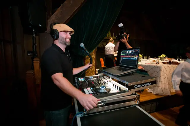 DJ Wayne Noel smiling at his controller during a reception at the Mill Valley Outdoor Art Club